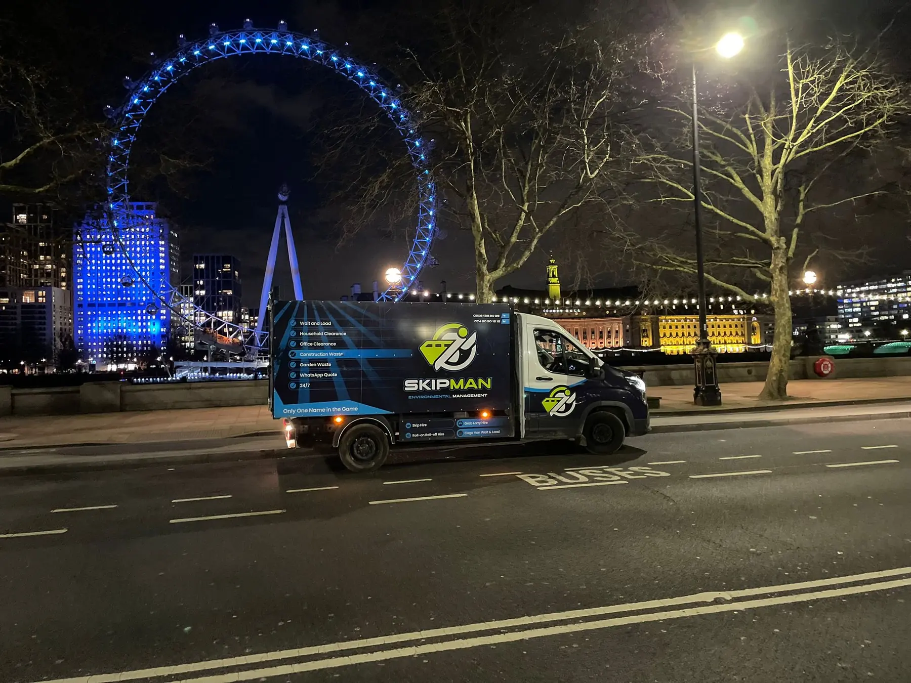 SKIPMAN branded cage van beside the London Eye at night